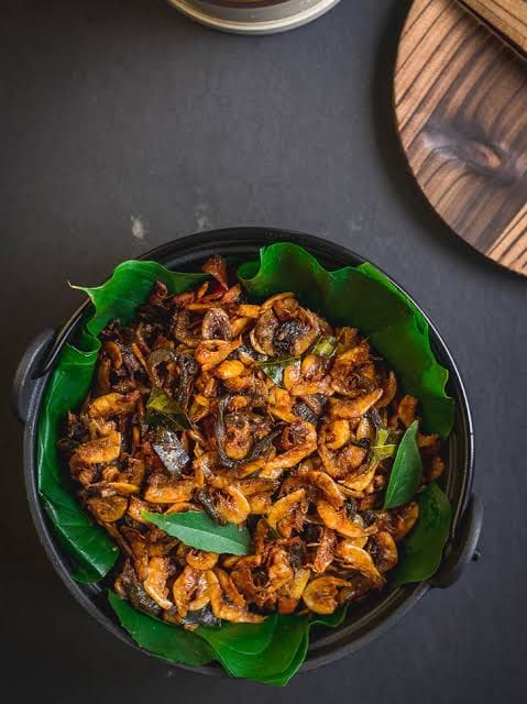 Kerala-style dried prawn roast served in a clay pot on banana leaf